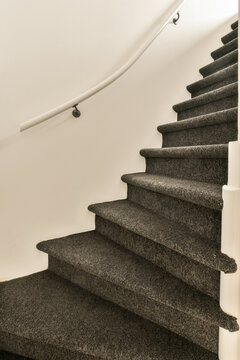 a carpeted staircase with white rail and gray carpet