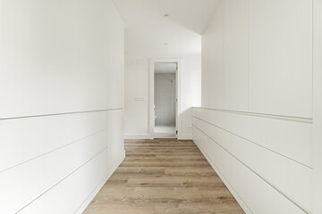 Hallway dressing room of a bedroom with access to a private bathroom with many drawers and white wooden cabinets