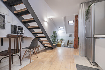 A loft-type home with a desk under a metal staircase