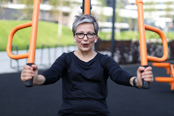 Senior woman finds relaxation and exercise in outdoor gym, embodying a healthy and happy lifestyle.