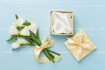 Fototapeta na wymiar Open gift box, with fresia flower wooden background, top view