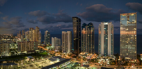 Aerial view of downtown district in Sunny Isles Beach city in Florida, USA. Brightly illuminated...