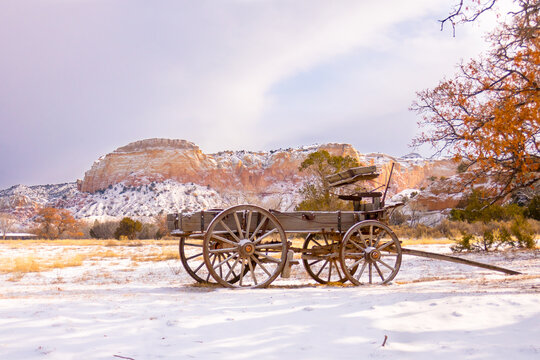 Abandoned buckboard wagon in the southwest at sunrise during winter with snow covered cliffs in background 