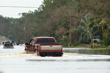Hurricane flooded street with moving cars in surrounded with water Florida residential area....