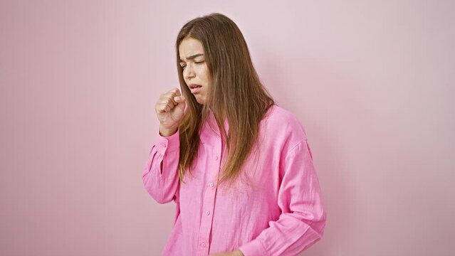 Stunning young hispanic woman, cool yet ill, coughing over a solitary pink backdrop. her beautiful hairstyle undone by flu; a portrait of sickness and strength.