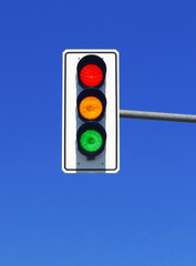 traffic light in blue sky with red, yellow and green lights on
