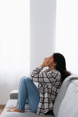 Chinese woman crying sitting on the sofa at home