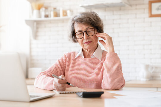 Concentrated Confused Old Elderly Senior Grandmother Woman Calculating, Accounting Doing Paperwork, Funds And Budget Audit At Home Kitchen, Solving Problems With Payments And Income. E-banking