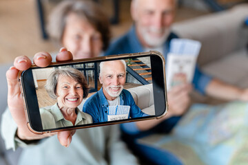 Caucasian senior old elderly couple grandparents traveling together, taking selfie before flight using cellphone, video calling vlogging blogging online. Active seniors concept