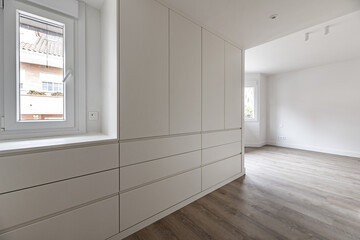 Newly installed bedroom dressing room with white wooden cabinets and drawers