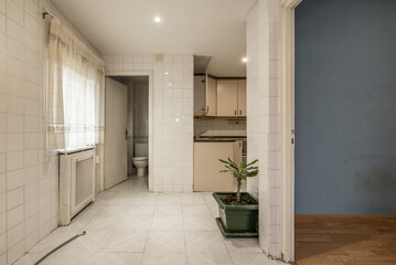 Empty kitchen with old white tiles, a window with curtains