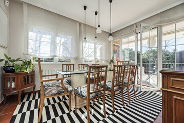 A dining table with a glass top, marble feet and a set of wooden chairs