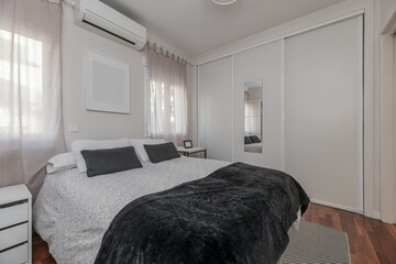 A bedroom with a double bed with a built-in wardrobe with white sliding wooden doors