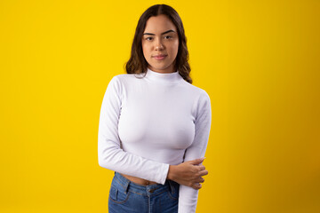 Young, happy woman wearing a white blouse, happy on yellow background