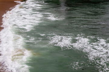 Moroccan atlantic sea waves with white foam on the sand.