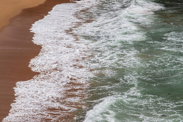 Moroccan atlantic sea waves with white foam on the sand.