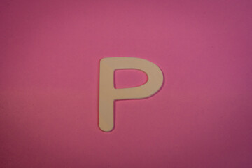 Letter P in wood on a pink background