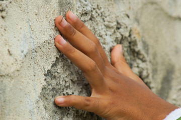 cropped-view of a hand touching stone wall