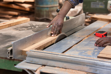 african man working with a saw blade wood working machine in the workshop cutting wood