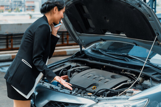 Young businesswoman whose car breakdown uses mobile phone to call for roadside assistance service. Travel and transportation vehicle problem. uds