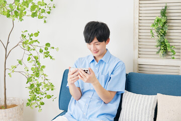 自宅でスマートフォンで動画を見る男性