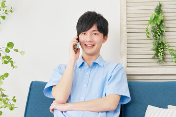 自宅でスマートフォンで電話する男性