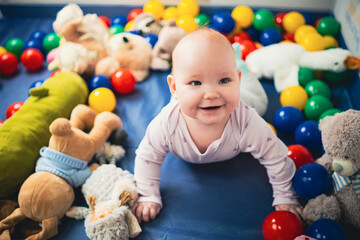 Cute baby girl playing with colorful toys in the nursery at home