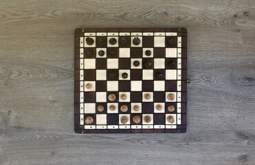 The chess board with the pieces in the dark vintage room interior