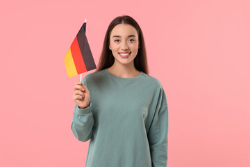 Young woman holding flag of Germany on pink background