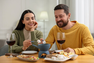 Fototapeta na wymiar Affectionate couple enjoying fondue during romantic date at home
