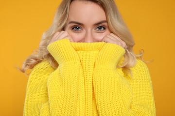 Beautiful woman in stylish warm sweater on orange background