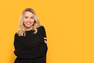 Obraz premium Happy woman in stylish warm sweater on orange background. Space for text