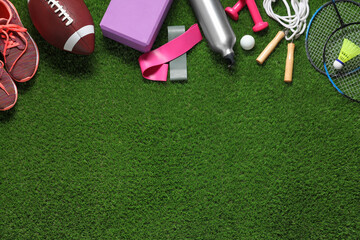 Naklejka premium Different sport tools on green grass, flat lay. Space for text
