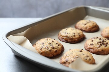 Baking pan with chocolate chip cookies on table, closeup