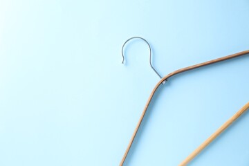 One wooden hanger on light blue background, top view. Space for text