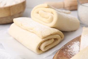 Fototapeta na wymiar Raw puff pastry dough on white table, closeup