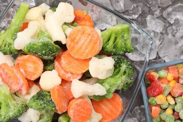Mix of different frozen vegetables with ice on grey table, flat lay