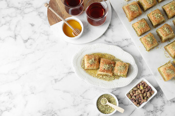 Delicious fresh baklava with chopped nuts served on white marble table, flat lay and space for text. Eastern sweets