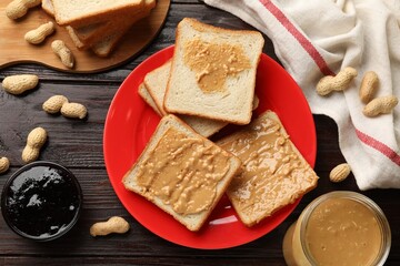Delicious toasts with peanut butter, nuts and jam on dark wooden table, flat lay