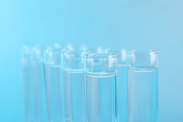 Laboratory analysis. Test tubes with liquid samples on light blue background, closeup