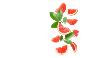 Fresh grapefruit pieces and green leaves falling on white background