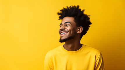 A young African American man exuding joy with a broad smile against a vibrant yellow advertising background.
