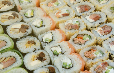 Close-up of a lot of sushi rolls with different fillings lie on a wooden surface. Macro shot of...