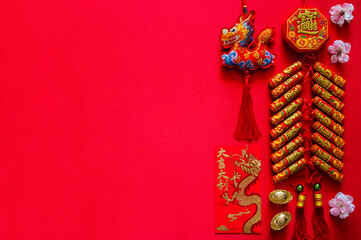 Firecrackers for Chinese new year (word mean wealth, blessing) with gold ingots (word mean wealth), red envelope packet (word mean good luck and good fortune) and pendant dragon on red background. - obrazy, fototapety, plakaty