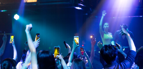 Fototapeta na wymiar music concert live on stage. Audience Captures the show with smartphone. diverse young people dancing in night club. Nightlife and disco dance party concept. Fun music festival