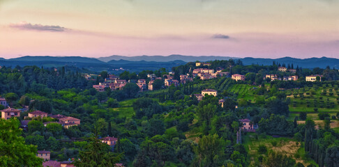 Obraz premium Tuscany rolling hills from Siena, rural misty evening landscape. Green farm fields with cypress trees. Italy 2023