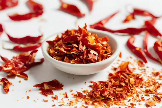 Red chili flakes sprinkled on a white surface, showcasing their vibrant color and spicy aroma