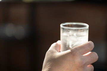 Hand holding water glass on black background.Thirsty woman holding glass drinks still water...