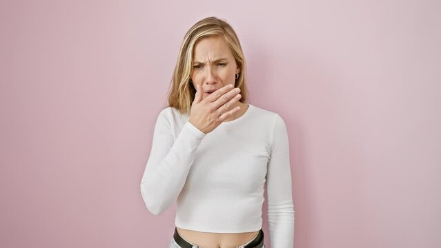 Young attractive blonde woman, standing over pink isolated background, displaying disgust. smelling intolerable stinky bad smell, holding breath with nose pinched.