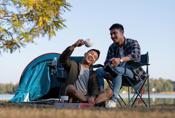 Asian LGBTQ couple drinking coffee in a romantic camping tent. LGBTQ couple drinking coffee in a camping tent, enjoying nature, forest, camping atmosphere, LGBTQ, gay, gay men.